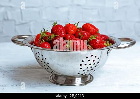 Reife Erdbeeren in Sieb auf Holztisch, Nahaufnahme Stockfoto