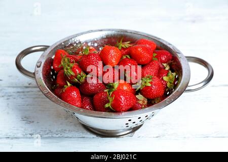 Reife Erdbeeren in Sieb auf Holztisch, Nahaufnahme Stockfoto