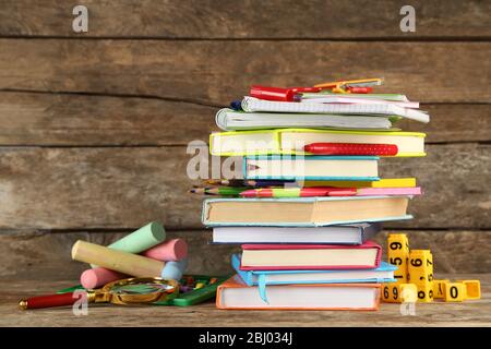 Stapel von Büchern und Schreibwaren auf Holzhintergrund Stockfoto