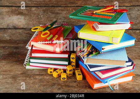 Stapel von Büchern und Schreibwaren auf Holzhintergrund Stockfoto