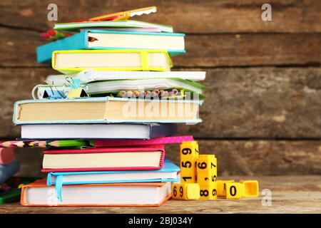 Stapel von Büchern und Schreibwaren auf Holzhintergrund Stockfoto