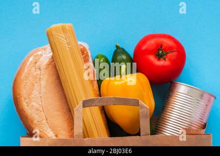 Papiertüte mit Lebensmittelzubehör auf blauem Hintergrund. Stockfoto