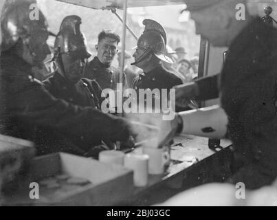 Feuerwehrleute erfrischend sich mit einer Tasse Tee nach der Bekämpfung von Abfällen Gummi Feuer. - 29. Oktober 1934 - - Stockfoto
