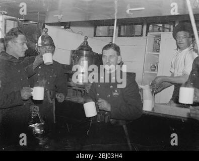 Feuerwehrleute erfrischend sich mit einer Tasse Tee nach der Bekämpfung von Abfällen Gummi Feuer. - 29. Oktober 1934 - - Stockfoto