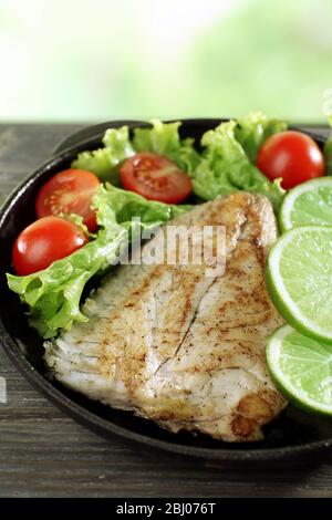 Fischfilet mit Salat und Limette auf hellem Hintergrund Stockfoto