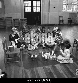 Während einer Pause in den Tag ' s Aktivitäten diese Säuglinge an der Jessop Primary School, Herne Hill, Südosten London genießen Sie eine Flasche Milch in der Schulhalle. - 12. Januar 1961 Stockfoto