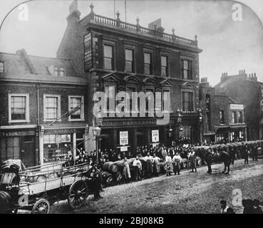 Der alte George in 379 Bethnal Green, London, England. - EINE große Menschenmenge und eine große Anzahl von Bierfässern säumen die Straße mit Brauereiarbeitern, die Tankards halten. - 1885 Stockfoto