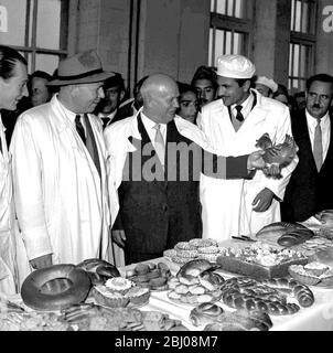 Schickes Brot für Chruschtschow. Kabul, Afghanistan. Sowjetischer Ministerpräsident Nikita S. Chruschtschow kichert, als er ein henne-förmiges Gebäck hochhält, als er durch die Bäckerei Kabul ging, die mit russischer Hilfe und technischer Aufsicht gebaut wurde. Der Premierminister besuchte Afghanistan während seiner Reise durch asiatische Länder. März 1960. Stockfoto