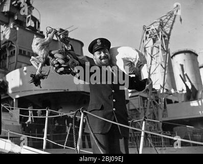 England Home und Booty. - Chief Petty Officer Alec Noble aus Portsmouth kommt vom Kreuzer HMS Devonshire (39) mit einer Bananenkuppel und einer türkei an Land. Seine Frau und fünf Töchter sind von einem frohen Weihnachtsfest überzeugt. HMS Devonshire, Dr. Plymouth am 30. November (Freitag) . Nach einer langen Kreuzfahrt im Pazifik. - 1. Dezember 1945 Stockfoto