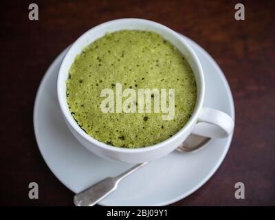 Köstliche einfache Kuchen mit gemahlenen Mandeln und Matcha Grüntee-Pulver, in einer Tasse in einer Mikrowelle gebacken. Stockfoto