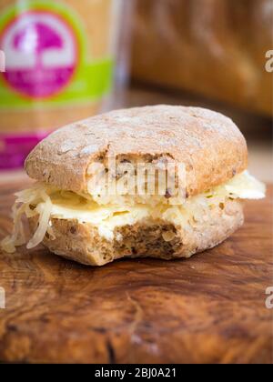 Nährendes Sandwich zum Mittagessen aus dünn geschnittenem Cheshire-Käse mit Sauerkraut auf braunem Ciabatta. (Glutenfreies Brot) Stockfoto