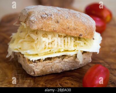 Nährendes Sandwich zum Mittagessen aus dünn geschnittenem Cheshire-Käse mit Sauerkraut auf braunem Ciabatta. (Glutenfreies Brot) Stockfoto