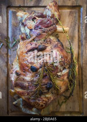 Langsam gebratene Lammschulter mit Knoblauch und Rosmarin, auf Holzschnitzbrett Stockfoto