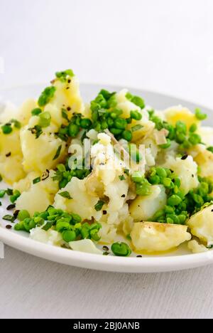 Kartoffel- und Erbsensalat mit Minze und Schnittlauch und grob gemahlenem schwarzem Pfeffer - Stockfoto