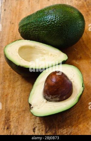 Ganze und schneiden frische Avocadobirne auf Holzhintergrund - Stockfoto