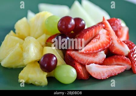 Frischer Obstsalat auf grünem Teller - Stockfoto