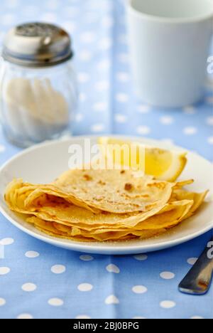 Pfannkuchen in Vierteln gefaltet mit Zucker auf und Zitronenkeil zum Quetschen - Stockfoto