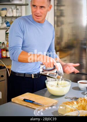 Gary Rhodes in der heimischen Küche, der Zutaten für ein festliches Brot und Butterpudding zuflüstert - Stockfoto