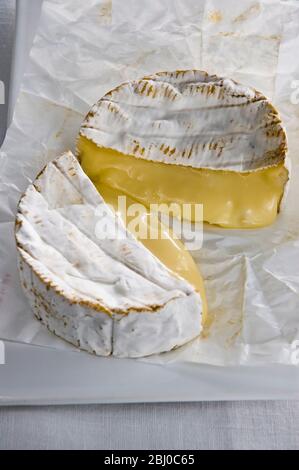 Runder Camembert Käse in zwei Hälften geschnitten mit reifer, laufender Innenausstattung - Stockfoto