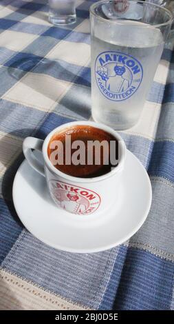Kleine Tasse starken griechischen Kaffee, mit Glas Wasser auf dem Tisch des Strandrestaurants im Süden Zyperns - Stockfoto