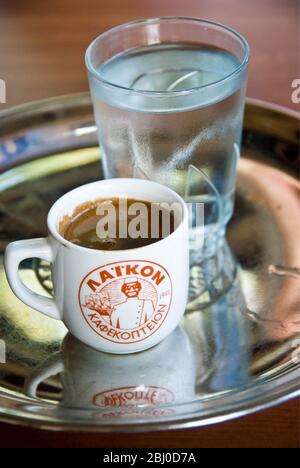 Kleine Tasse starken griechischen Kaffee, mit Glas Wasser auf Tablett auf dem Tisch des Hangrestaurants im Süden Zyperns - Stockfoto
