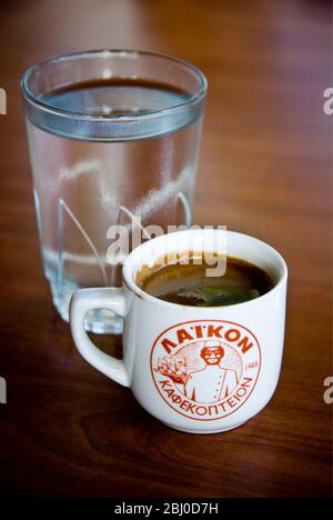Kleine Tasse starken griechischen Kaffee, mit Glas Wasser auf Tablett auf dem Tisch des Hangrestaurants im Süden Zyperns - Stockfoto