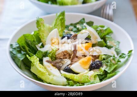 Weiße Schüssel mit klassischer Salade Nicoise, mit Vinaigrette - Stockfoto