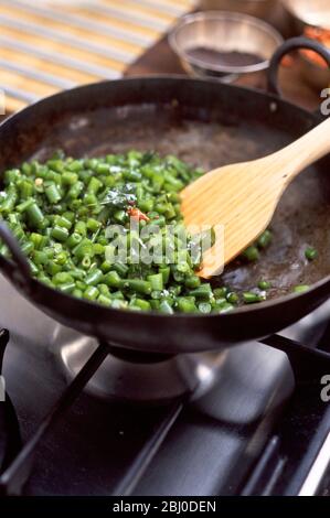 Stirbrying grüne Bohnen mit Gewürzen und Limettenblättern für indische Gerichte - Stockfoto