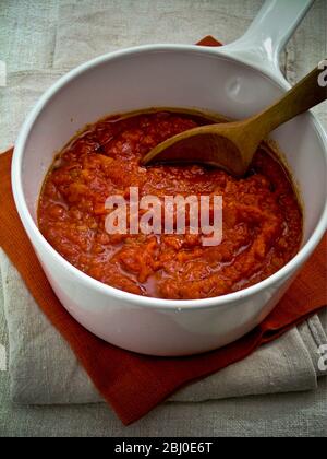 Tonato-Sauce in einem weißen Keramikkochtopf unter Rühren mit einem Holzlöffel - Stockfoto