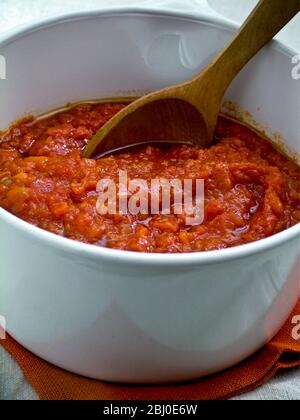 Tonato-Sauce in einem weißen Keramikkochtopf unter Rühren mit einem Holzlöffel - Stockfoto