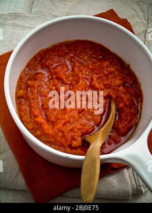 Tonato-Sauce in einem weißen Keramikkochtopf unter Rühren mit einem Holzlöffel - Stockfoto