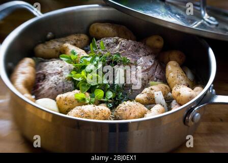 Lammhalsstücke mit Gewürzen und frischen Kräutern mit kleinen Anya-Kartoffeln in breiter Pfanne - Stockfoto