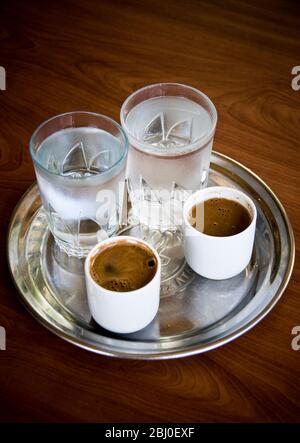 Zwei kleine Tassen griechischen Kaffee mit begleitenden Gläsern Wasser serviert in zypriotischen Café in den Hügeln im Süden Zyperns - Stockfoto