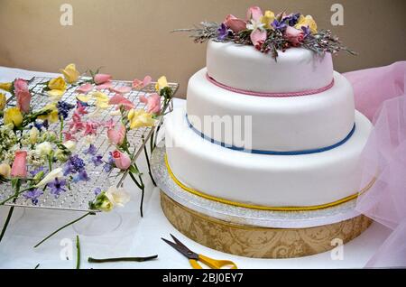 Hochzeitstorte oder Festtorte, mit zuckermatten Blüten und pastellfarbenen Schnüren dekoriert. - Stockfoto
