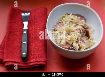 Kleines weißes Gericht aus deutschem Sauerkraut mit geräucherten Wurststücken - Stockfoto