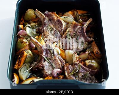 Schweinebraten mit gemischtem Bratgemüse, gewürzt mit schwarzem Pfeffer und frischen Rosmarinzweigen. - Stockfoto