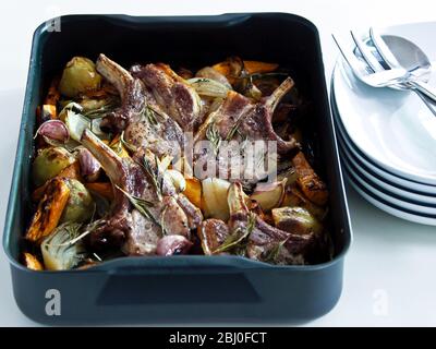 Schweinebraten mit gemischtem Bratgemüse, gewürzt mit schwarzem Pfeffer und frischen Rosmarinzweigen. - Stockfoto