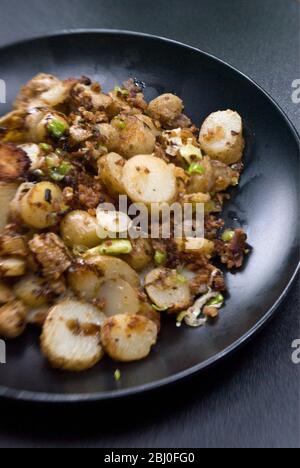 Gericht mit gebratenen Kartoffeln, mit Sardellen, Frühlingszwiebeln und Semmelbröseln anbraten. - Stockfoto