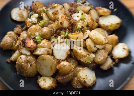 Gericht mit gebratenen Kartoffeln, mit Sardellen, Frühlingszwiebeln und Semmelbröseln anbraten. - Stockfoto