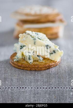 Stilton Käse auf einem Weizenknacker auf Leinentischdecke. - Stockfoto