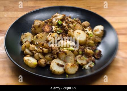 Gericht mit gebratenen Kartoffeln, mit Sardellen, Frühlingszwiebeln und Semmelbröseln anbraten. - Stockfoto