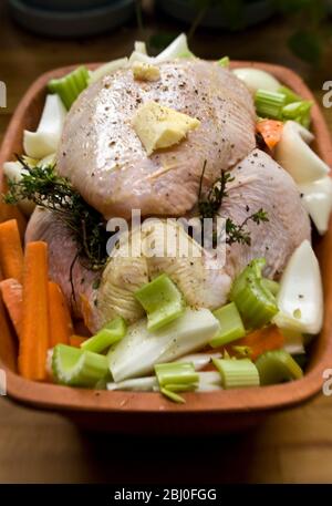 Hühnchen für den Ofen in einem Terracotta-Hühnerstein mit Zwiebeln, Sellerie, Karotten, Thymian und ein wenig Weißwein zubereitet - Stockfoto
