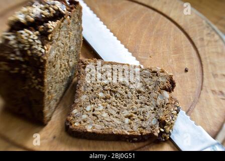 Scheibe grobes Roggenbrot nach skandinavischem Stil auf Holzbrotbrett. - Stockfoto