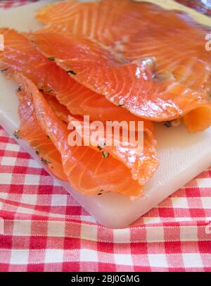 Frisch geschnittene Gravlax-Stücke auf weißem Brett und gechillter Tischdecke - Stockfoto