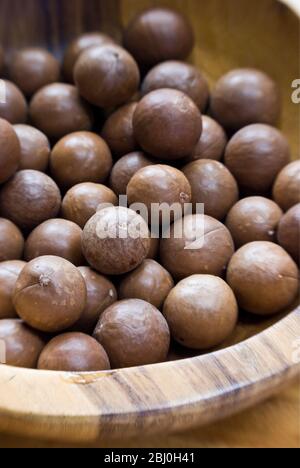 Ganze Macadamianüsse in ihren Schalen in Holzschale - Stockfoto