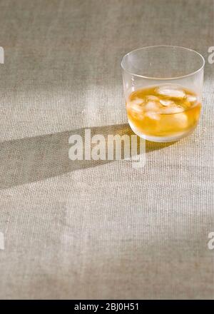 Glas Whisky mit Eis auf rauem hessischem Tuch - Stockfoto