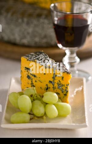 Blacksticks Blue Cheese aus Lancashire UK, serviert auf Teller mit Trauben und einem Glas Rotwein - Stockfoto