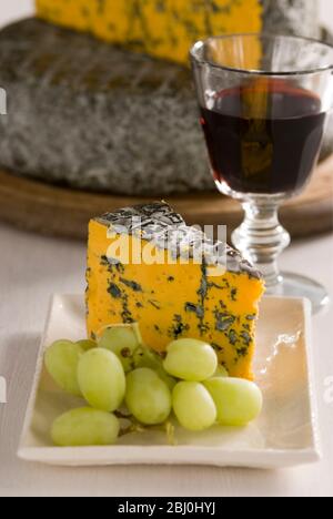 Blacksticks Blue Cheese aus Lancashire UK, serviert auf Teller mit Trauben und einem Glas Rotwein - Stockfoto