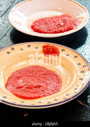 Zwei Sorten Tomatenmark - Passata und Passata Rustico auf italienischen Tellern - Stockfoto