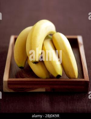 Hand' von Bananen auf Holztablett - Stockfoto